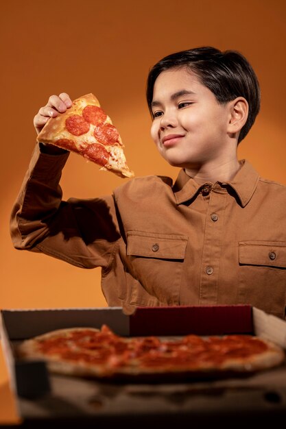 Niño de tiro medio sosteniendo pizza