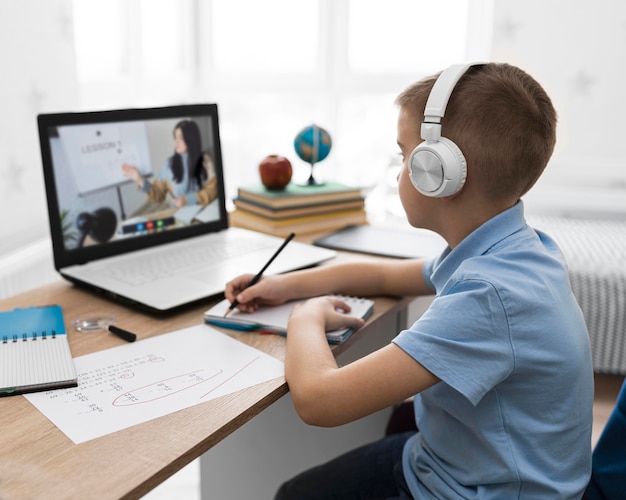 Niño de tiro medio tomando notas