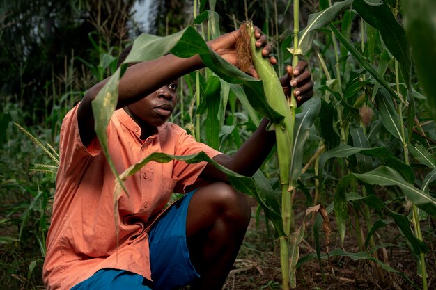 Niño de tiro medio trabajando en el maizal