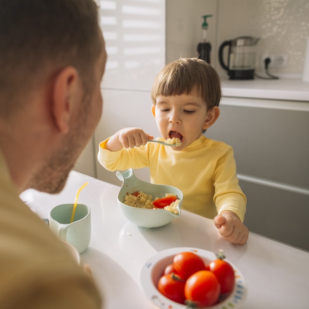 Niño tomando cereales con cuchara y come