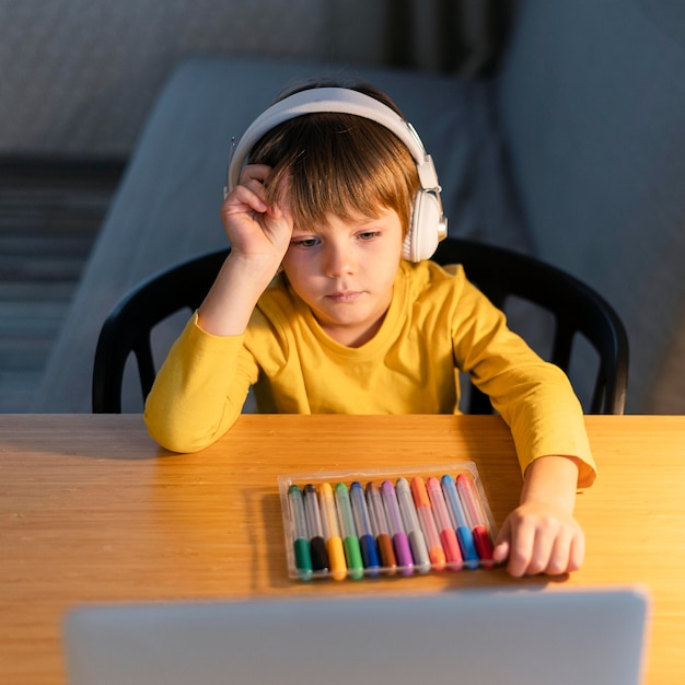 Niño tomando cursos virtuales y con marcadores de colores.