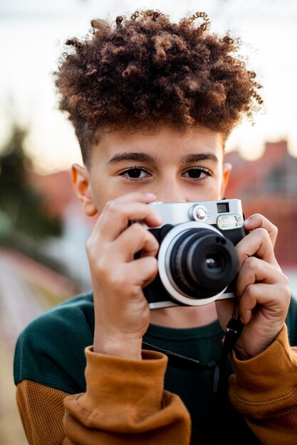 Niño tomando una foto con su cámara afuera