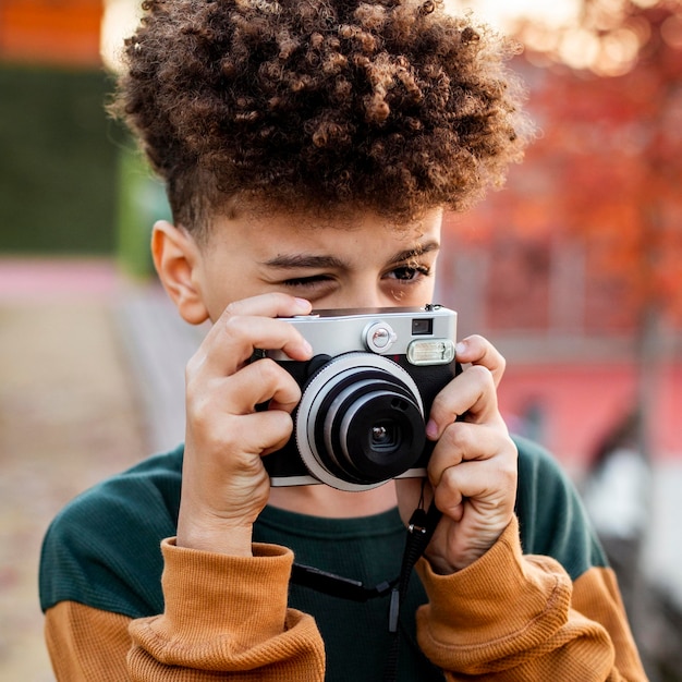 Foto gratuita niño tomando una foto con su cámara al aire libre