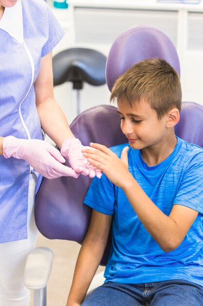 Niño tomando pastillas de dentista mano en clínica