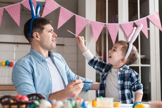 Foto gratuita niño tratando de pintar a su padre