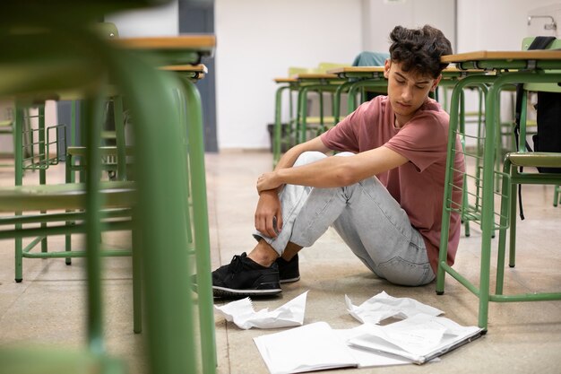 Niño triste de tiro completo en el aula