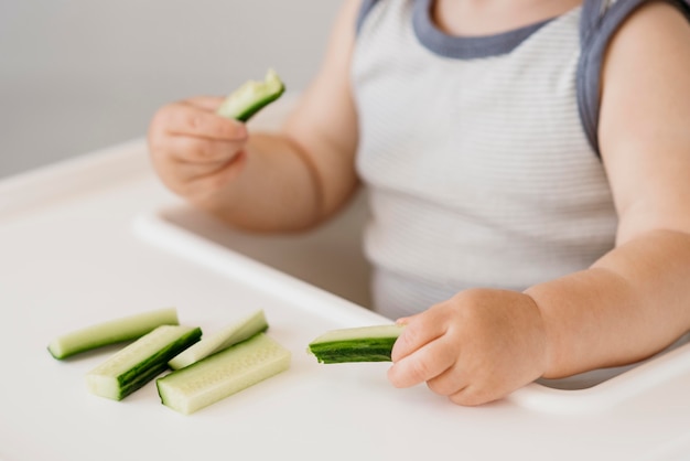 Niño en trona con trozos de pepino