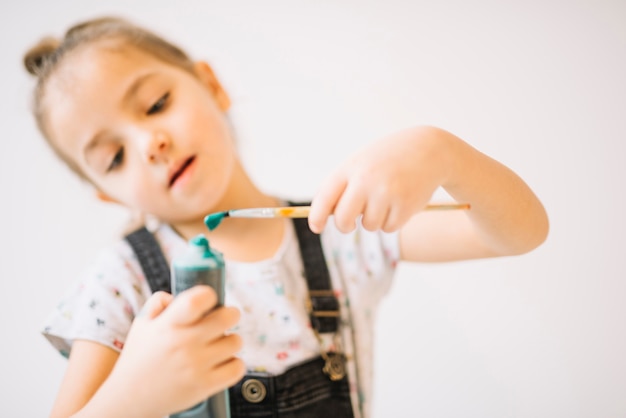 Foto gratuita niño con tubo de colores y pincel en manos.