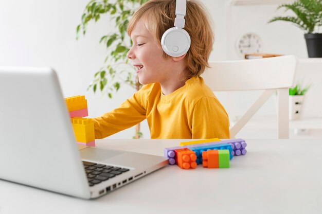 Niño usando auriculares y portátil en casa