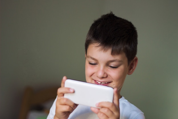 Niño usando un teléfono inteligente móvil y sonriendo