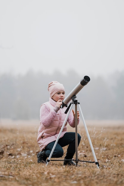Niño usando un telescopio afuera