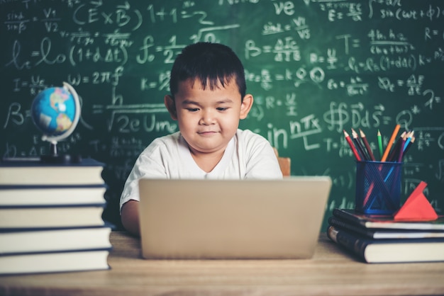 niño use computadora portátil en el aula.