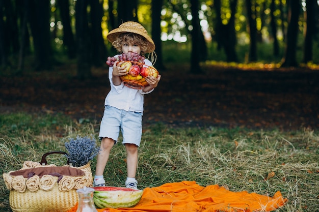 Niño con uvas en el bosque en un picnic