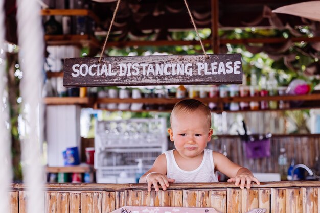 Niño de vacaciones en Tailandia con signo de distancia social en el bar