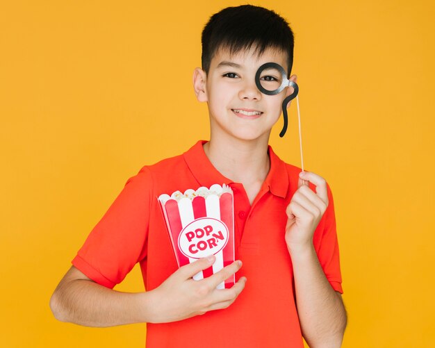 Niño vestido con un monóculo falso con fondo naranja