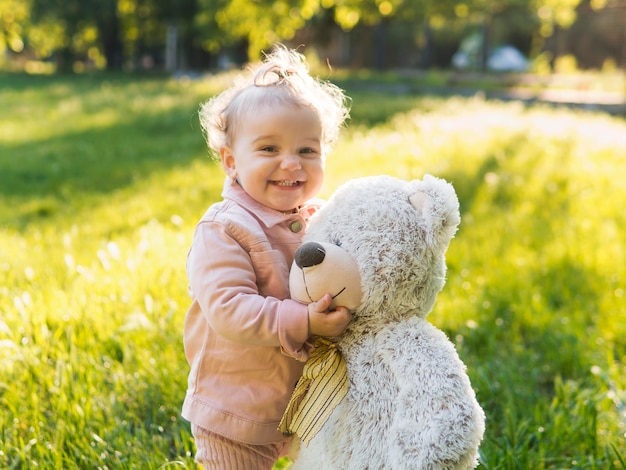 Niño vestido con ropa rosa y oso de peluche en el parque