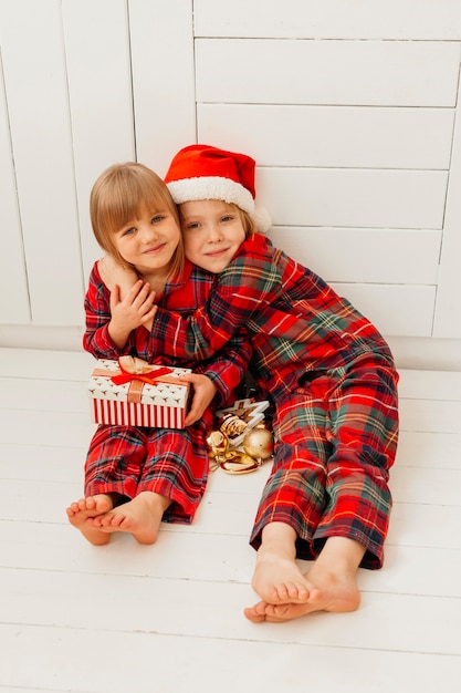 Niño de vista frontal abrazando a su hermana el día de Navidad