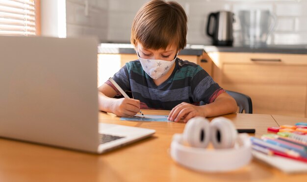 Niño de vista frontal aprendiendo de clases virtuales