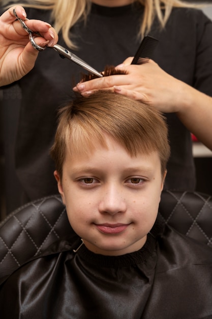 Niño de vista frontal cortándose el pelo en el salón