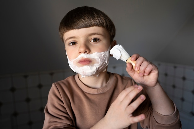Niño de vista frontal usando crema de afeitar