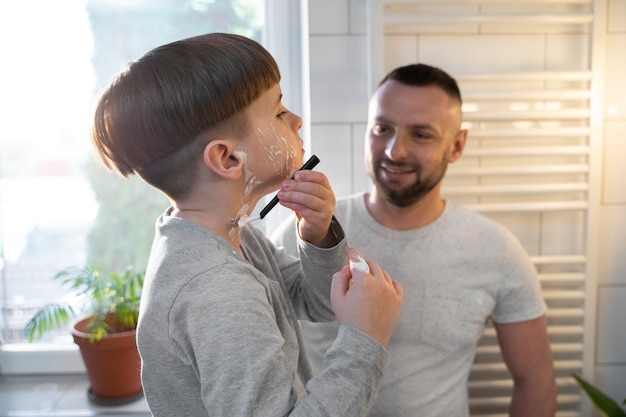 Niño de vista lateral aprendiendo a afeitarse en casa