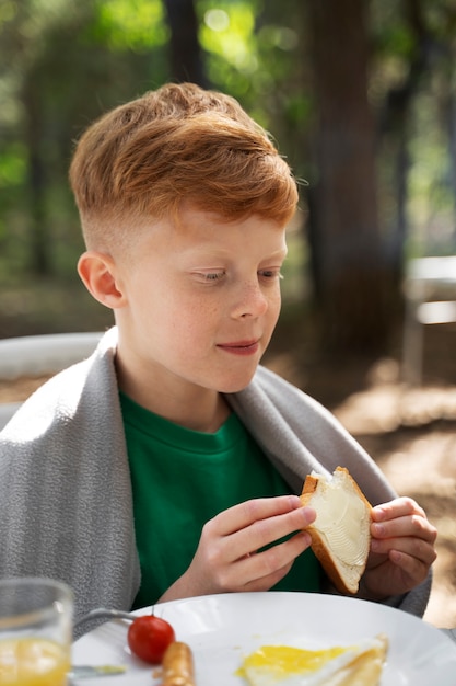 Foto gratuita niño de vista lateral comiendo en la naturaleza