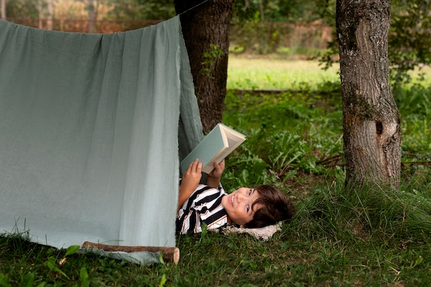 Foto gratuita niño de vista lateral leyendo al aire libre