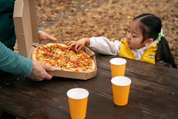 Niño de vista lateral tomando rebanada de pizza