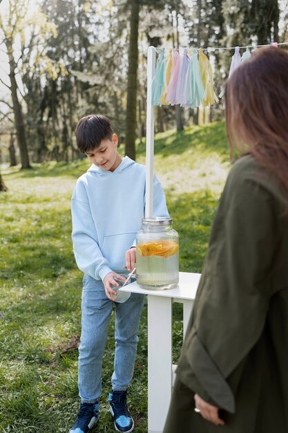 Niño de vista lateral vendiendo limonada