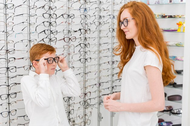 Niño vistiendo espectáculo delante de su joven hermana en la tienda de óptica