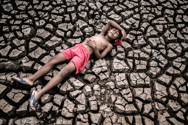 El niño yacía plano, apoyando las manos sobre el vientre y la frente en tierra seca.