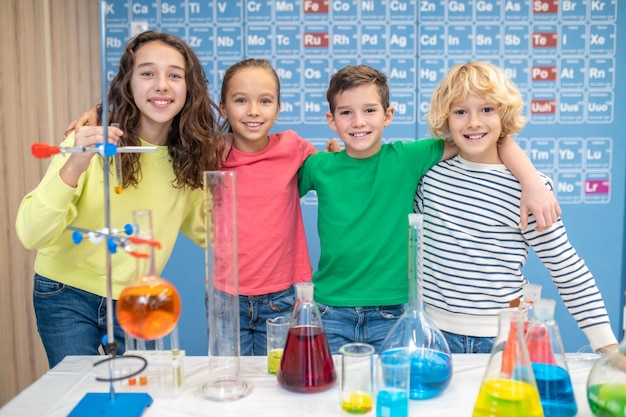 Niños abrazándose mirando a la cámara en clase de química