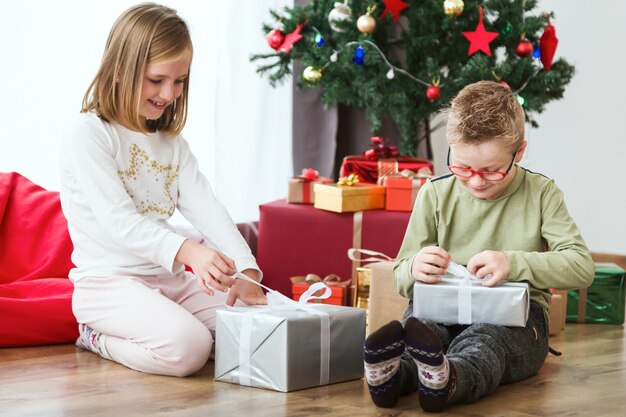 Niños abriendo regalos de navidad en el suelo