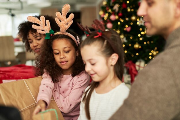 Niños abriendo regalos de Navidad con sus padres.