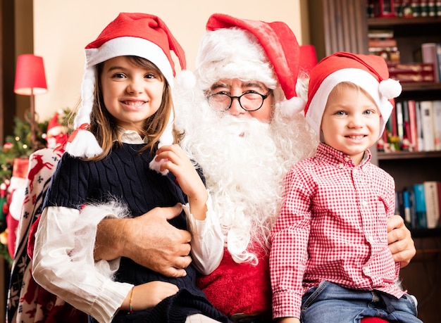 Niños adorables sentados en las piernas de papa noel en navidad