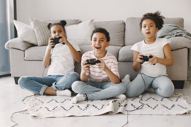 Niños africanos jugando videojuegos. Niños con ropa ligera. Controlador en manos de los niños.