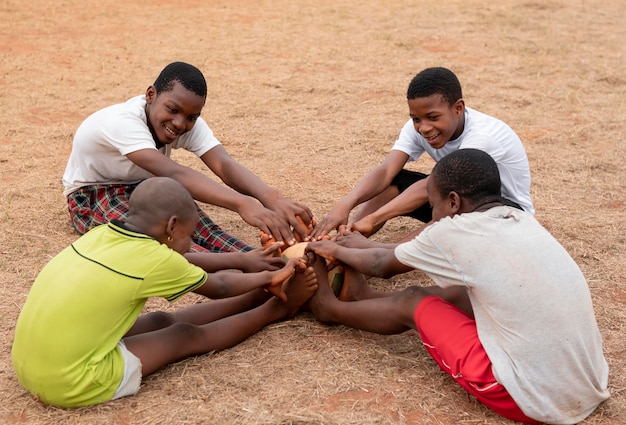 Niños africanos con pelota de fútbol sentado