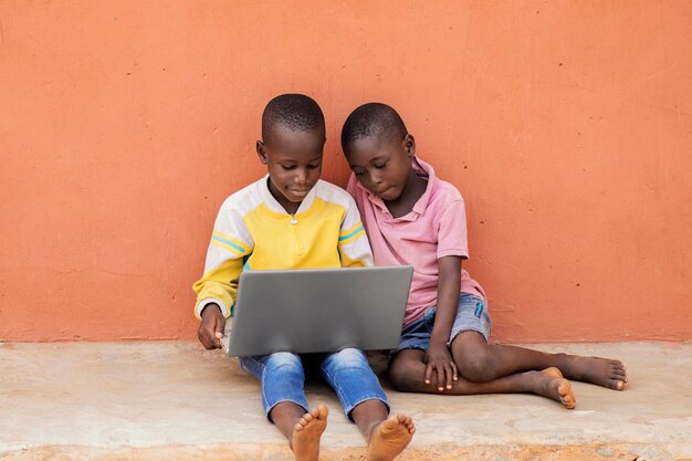 Niños africanos de tiro completo con laptop
