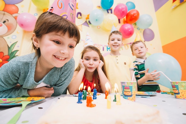 Niños alegres que miran la torta de cumpleaños