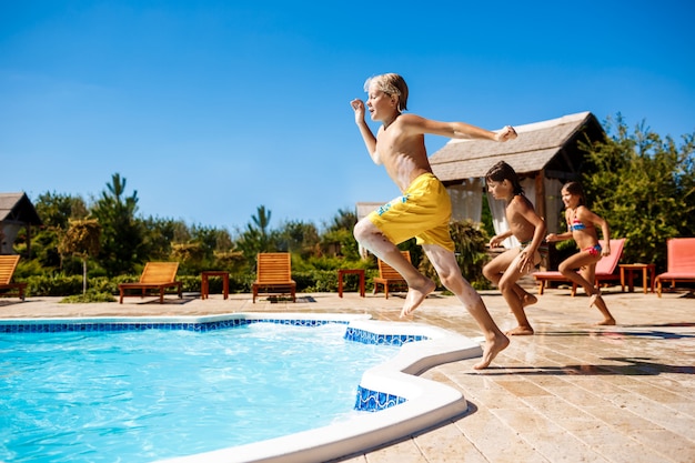 Foto gratuita niños alegres regocijándose, saltando, nadando en la piscina.