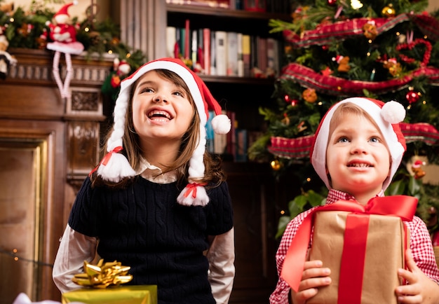 Niños alegres sujetando regalos de navidad