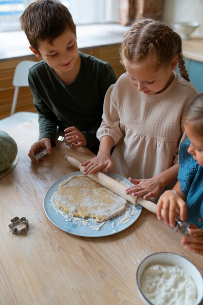 Niños de alto ángulo cocinando juntos en el interior