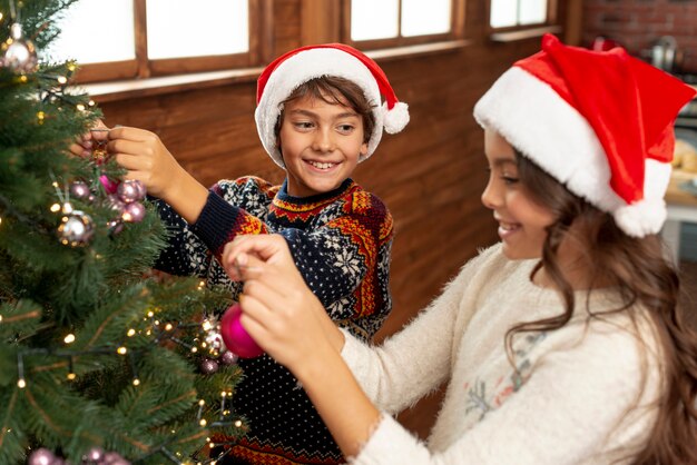 Niños de alto ángulo decorando el árbol de navidad
