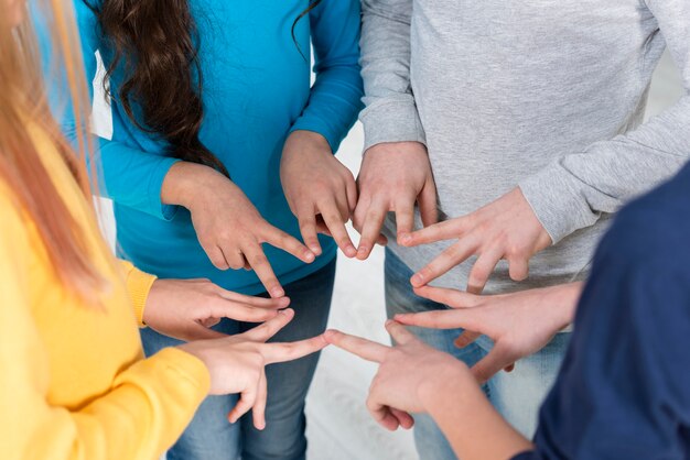 Niños de alto ángulo formando marco de signo de la paz con las manos