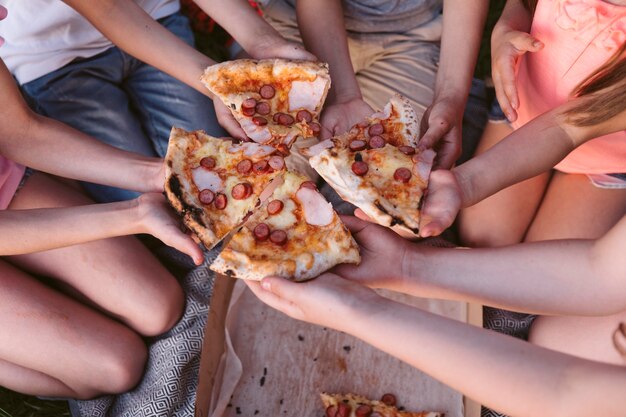 Niños de alto ángulo tomando una rebanada de pizza