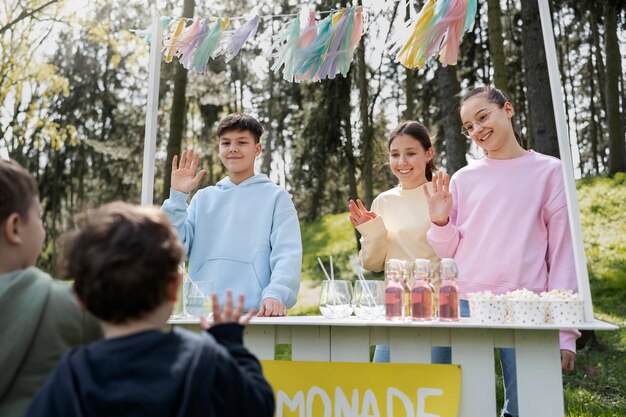 Niños de ángulo bajo vendiendo limonada.