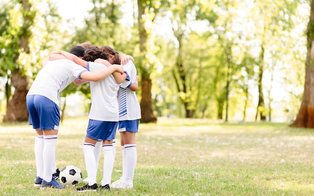 Foto gratuita los niños se animan unos a otros antes de un partido de fútbol con espacio de copia