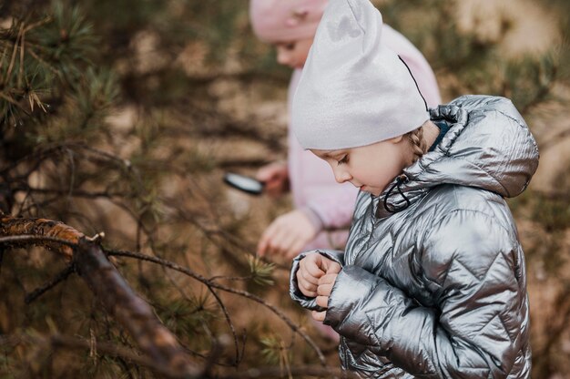 Niños aprendiendo ciencias en la naturaleza con una lupa.