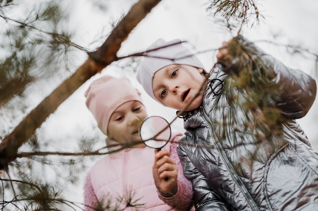 Niños aprendiendo ciencias en la naturaleza con una lupa.