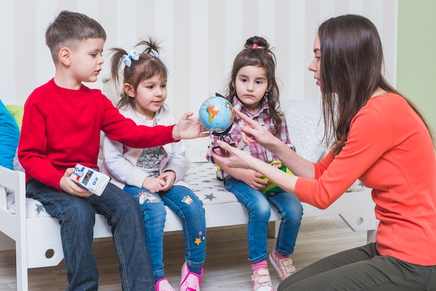 Niños aprendiendo globo con mujer en el dormitorio